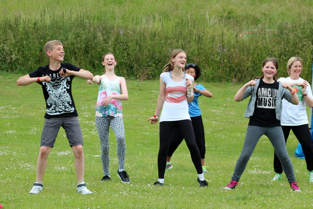 Young people dance together outside at a Wild Park community event